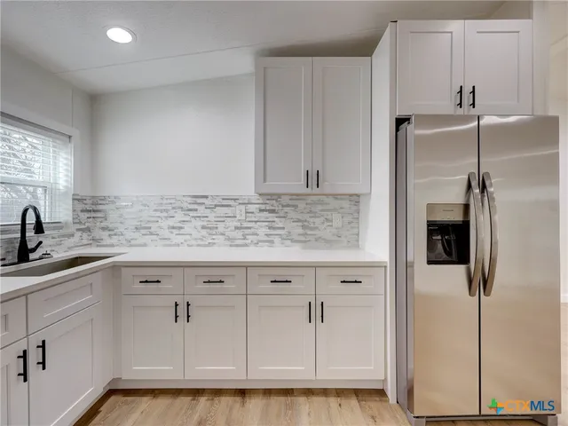 a kitchen with white cabinets and refrigerator