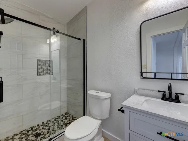 a bathroom with a sink a toilet and shower