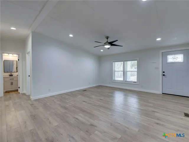 a view of an empty room with glass door and wooden floor