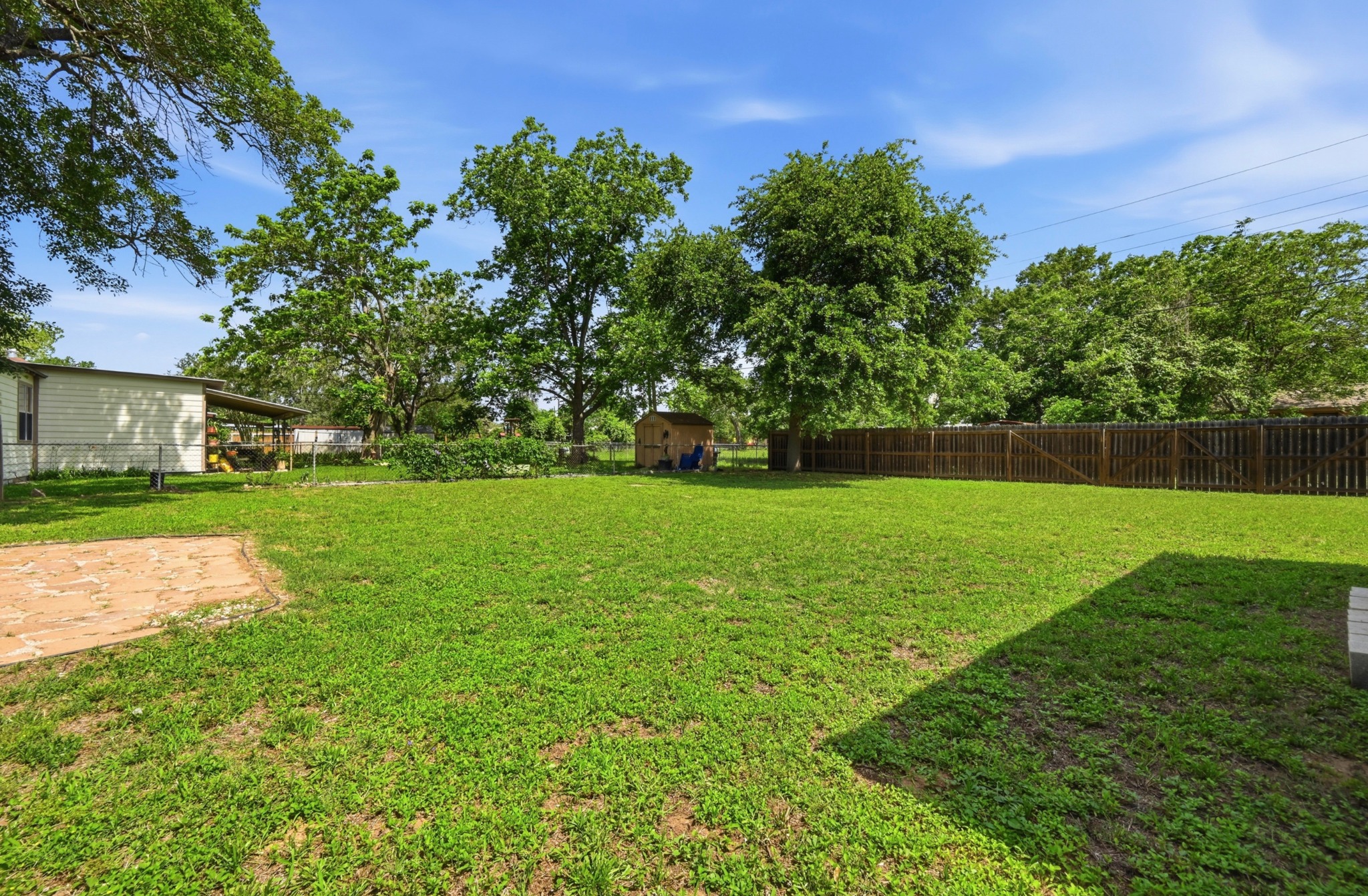 1127 Parr Street Luling, TX 78648 - Photo 19 of 20 A spacious backyard with mature trees, a wooden shed, and a privacy fence.