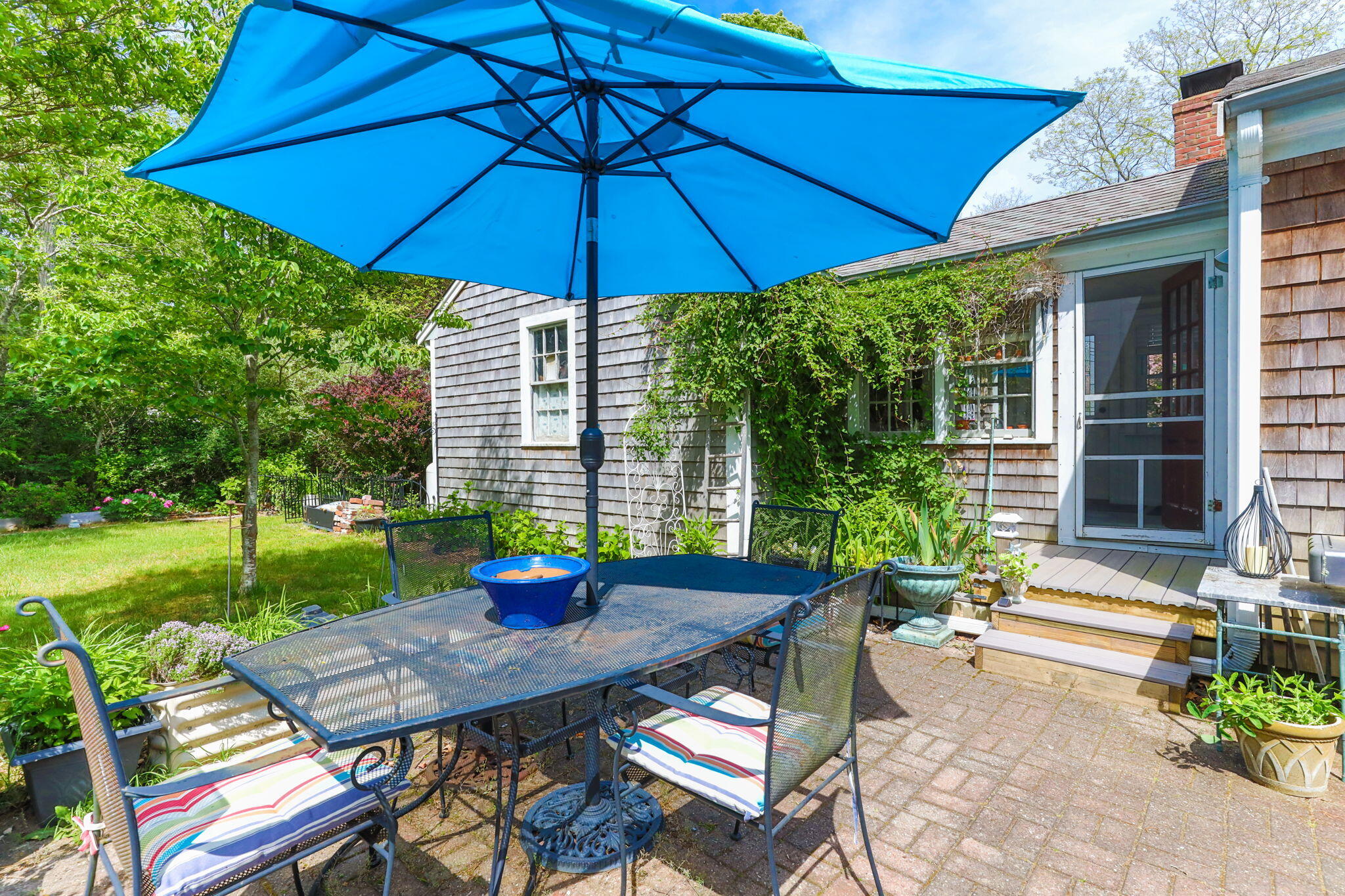 4975 State Highway, Unit A Eastham, MA 02642 - Photo 37 of 44 a view of a backyard with table and chairs under an umbrella