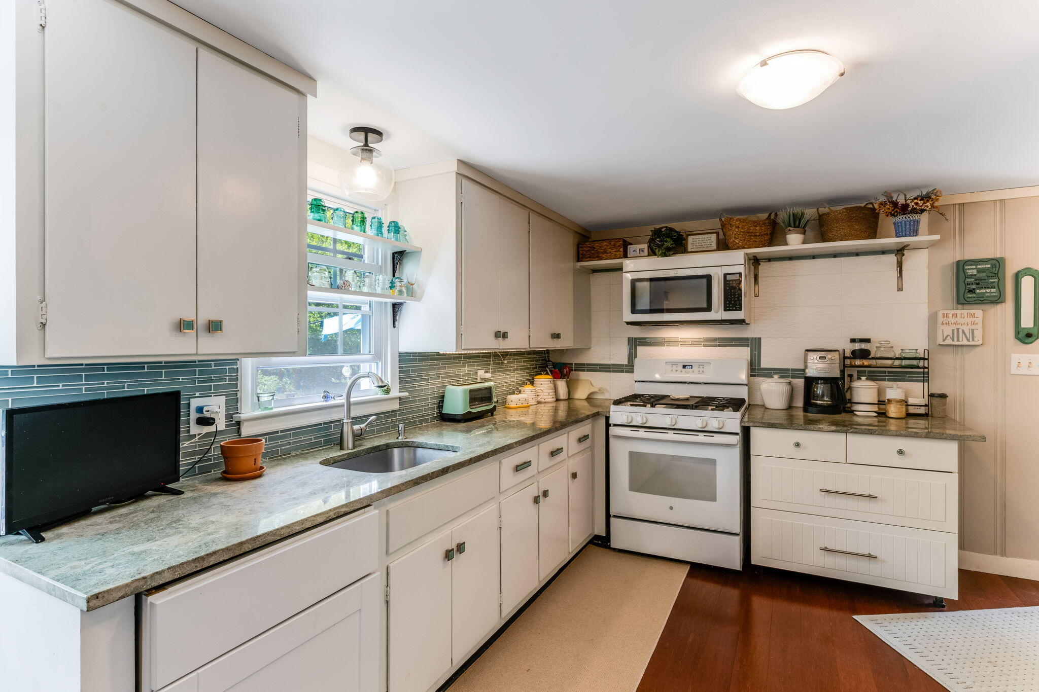 4975 State Highway, Unit A Eastham, MA 02642 - Photo 10 of 44 a kitchen with granite countertop a sink stainless steel appliances and white cabinets