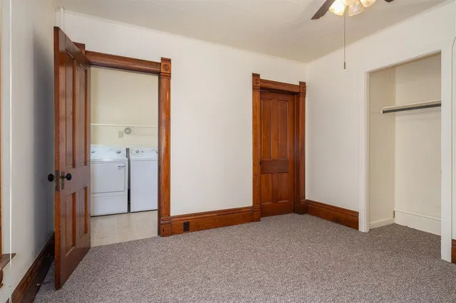 an empty room with closet and a chandelier fan