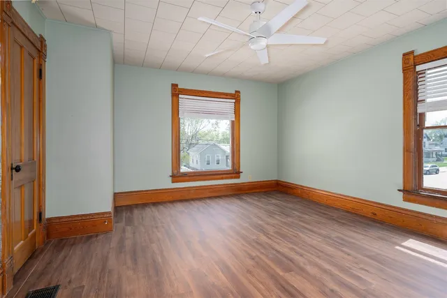 an empty room with wooden floor and windows
