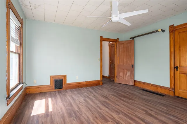 a view of empty room with wooden floor and fan