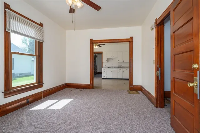 an empty room with chandelier fan and windows