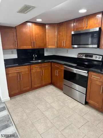 a kitchen with stainless steel appliances granite countertop a stove a sink and a microwave