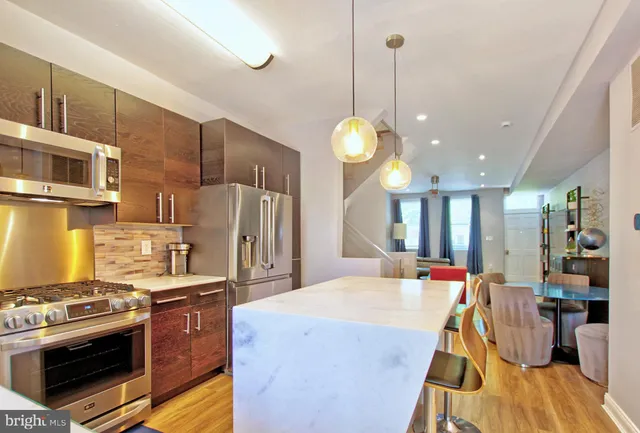 a kitchen with stainless steel appliances granite countertop a stove a kitchen island a refrigerator and a sink