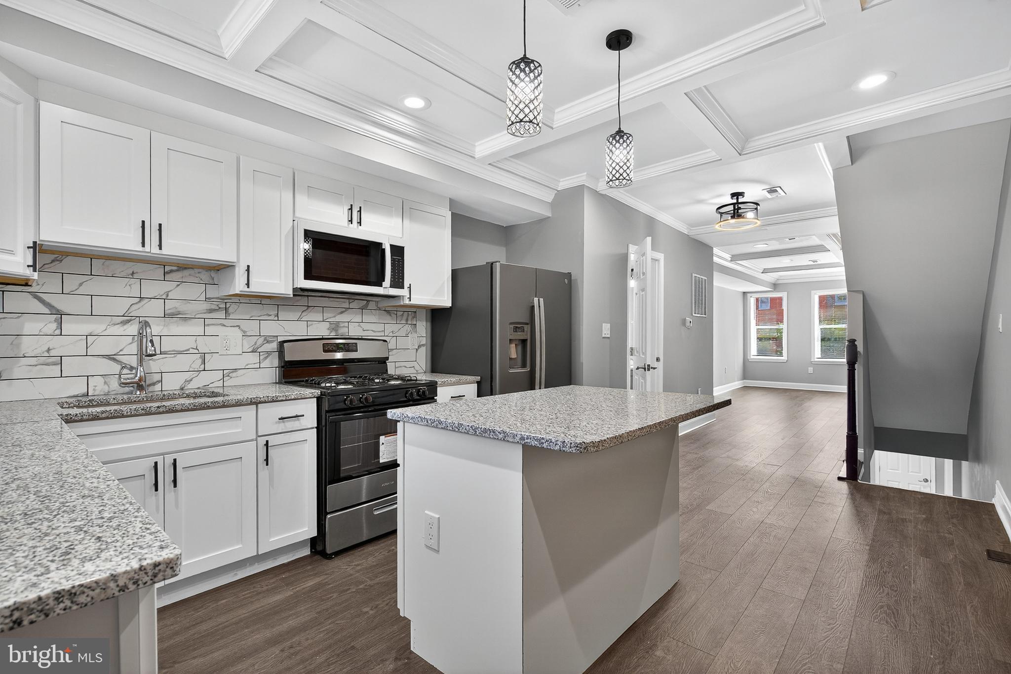 a kitchen with stainless steel appliances kitchen island granite countertop a refrigerator a stove top oven a sink dishwasher and white cabinets with wooden floor