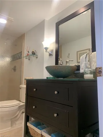 a bathroom with a granite countertop sink a toilet a mirror and shower