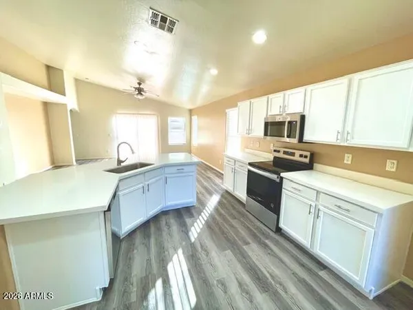 a kitchen with stainless steel appliances a sink wooden floor and window