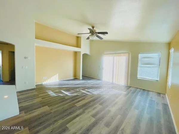 a view of empty room with wooden floor and fan
