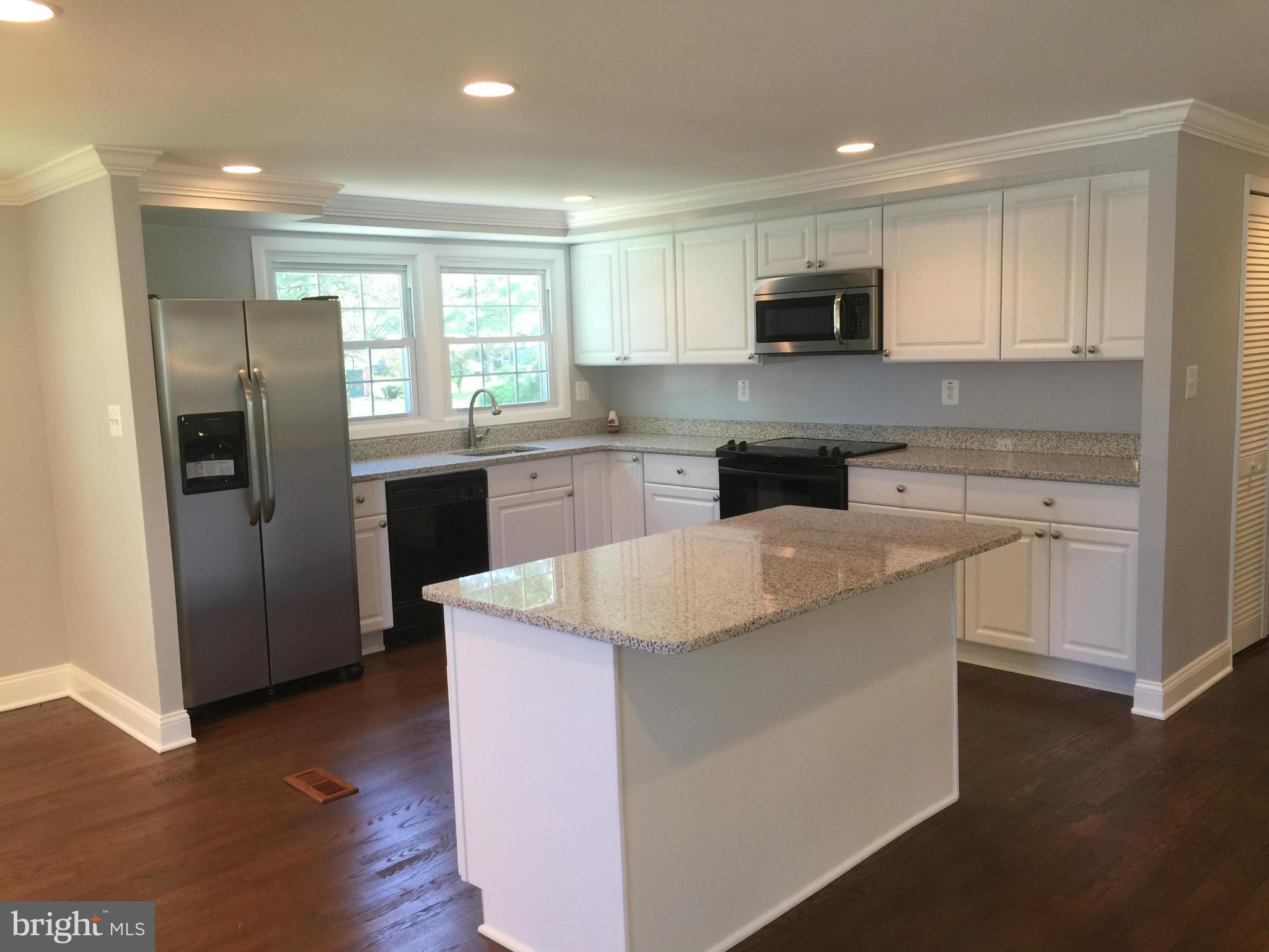 5146 Downwest Ride Columbia, MD 21044 - Photo 4 of 26 a kitchen with stainless steel appliances granite countertop a stove top oven a refrigerator a sink and dishwasher with wooden floor