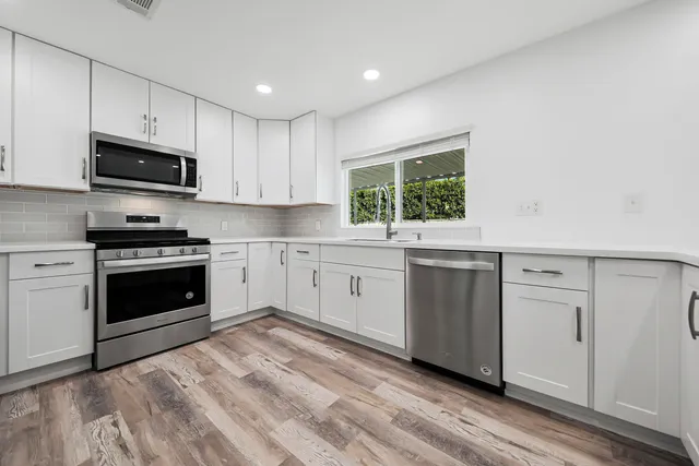 a kitchen with granite countertop white cabinets and stainless steel appliances