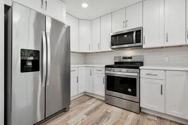 a kitchen with stainless steel appliances a refrigerator stove and white cabinets