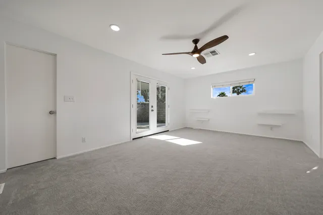 an empty room with windows and fan