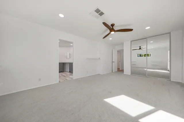 an empty room with a ceiling fan and hallway