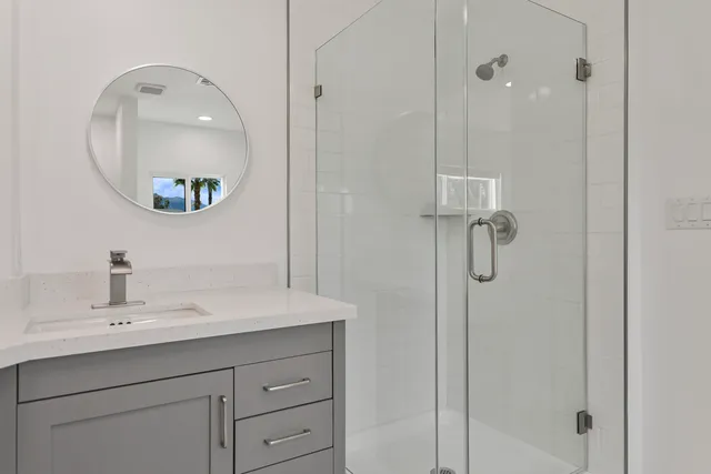 a bathroom with a sink a mirror a vanity and a shower