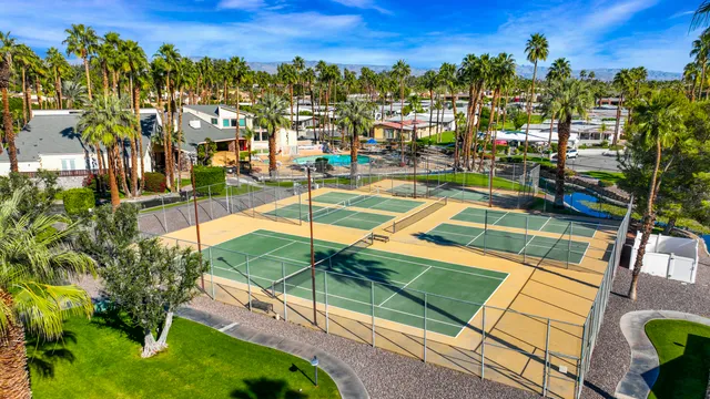 a view of a tennis ground with large trees