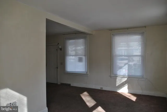 an empty room with wooden floor cabinet and windows