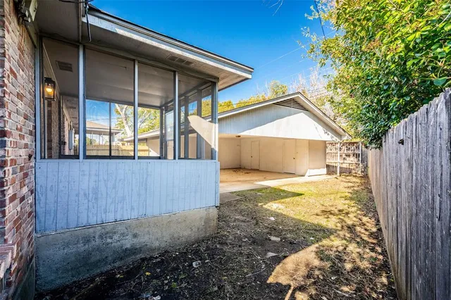 a view of a small house with backyard and wooden fence