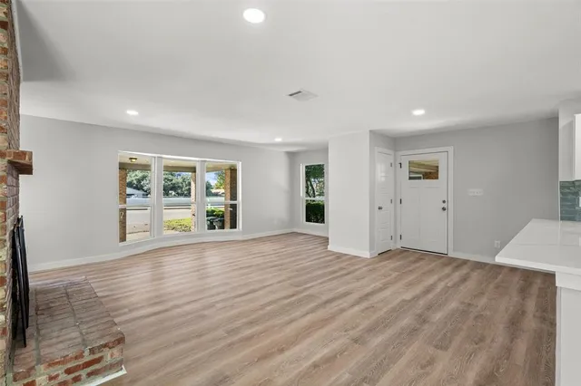 a view of an empty room with a window and wooden floor