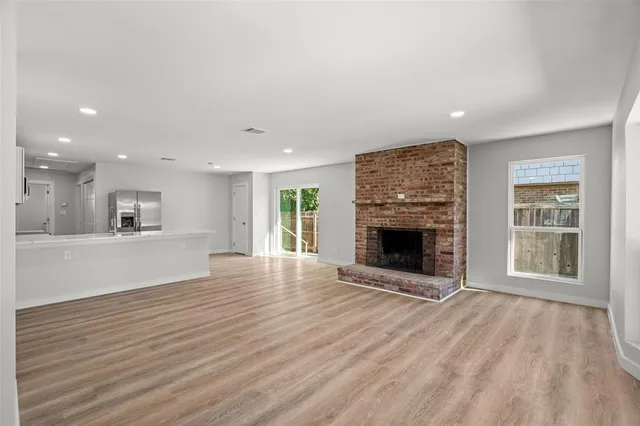 an empty room with wooden floor a fireplace and windows