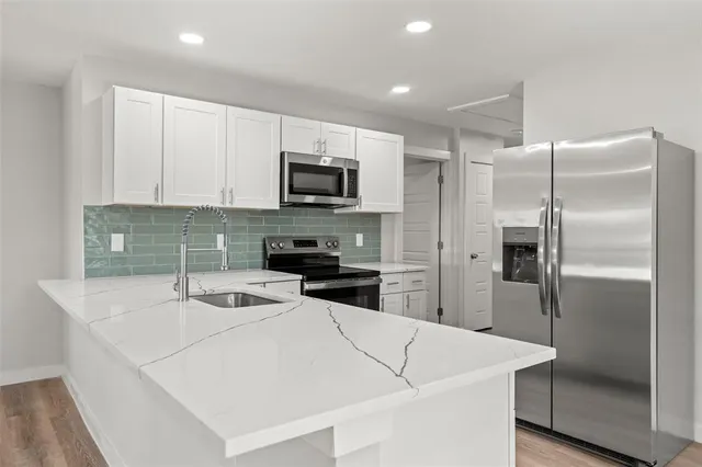 a kitchen with kitchen island a sink stainless steel appliances and refrigerator