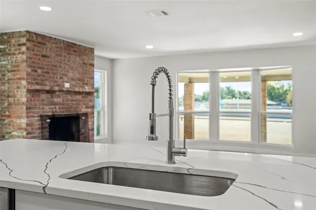 a view of a kitchen with a sink and dishwasher with a fireplace