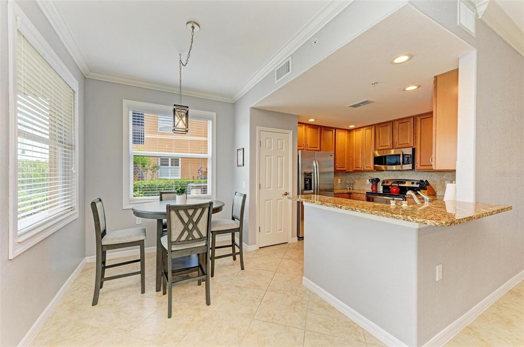 424 Winding Brook Lane, Unit 104 Bradenton, FL 34212 - Photo 29 of 72 a kitchen with stainless steel appliances kitchen island granite countertop a sink and a refrigerator