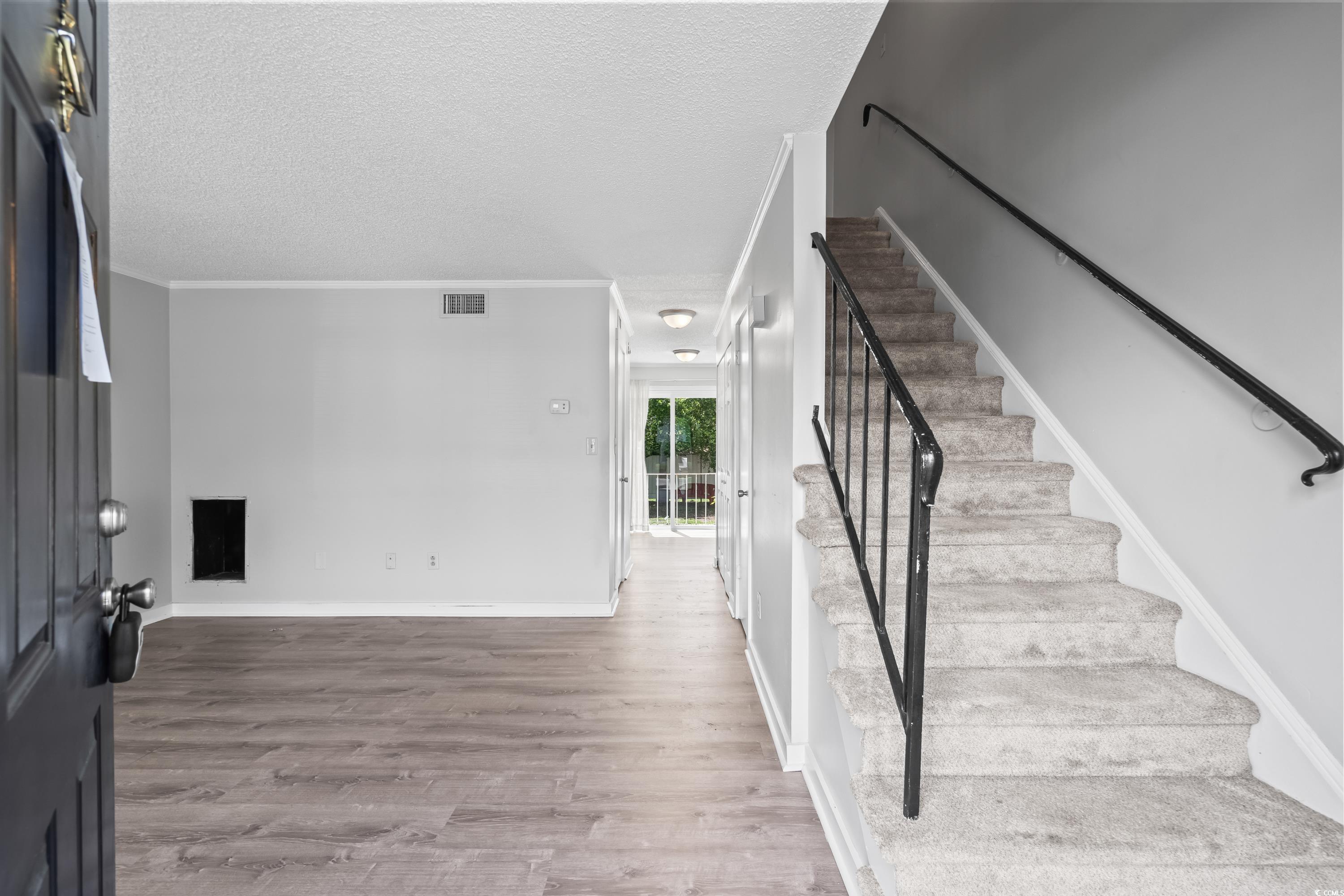 4115 Little River Road, Unit 1E Myrtle Beach, SC 29577 - Photo 3 of 38 Stairway with wood finished floors, a textured ceiling, and crown molding