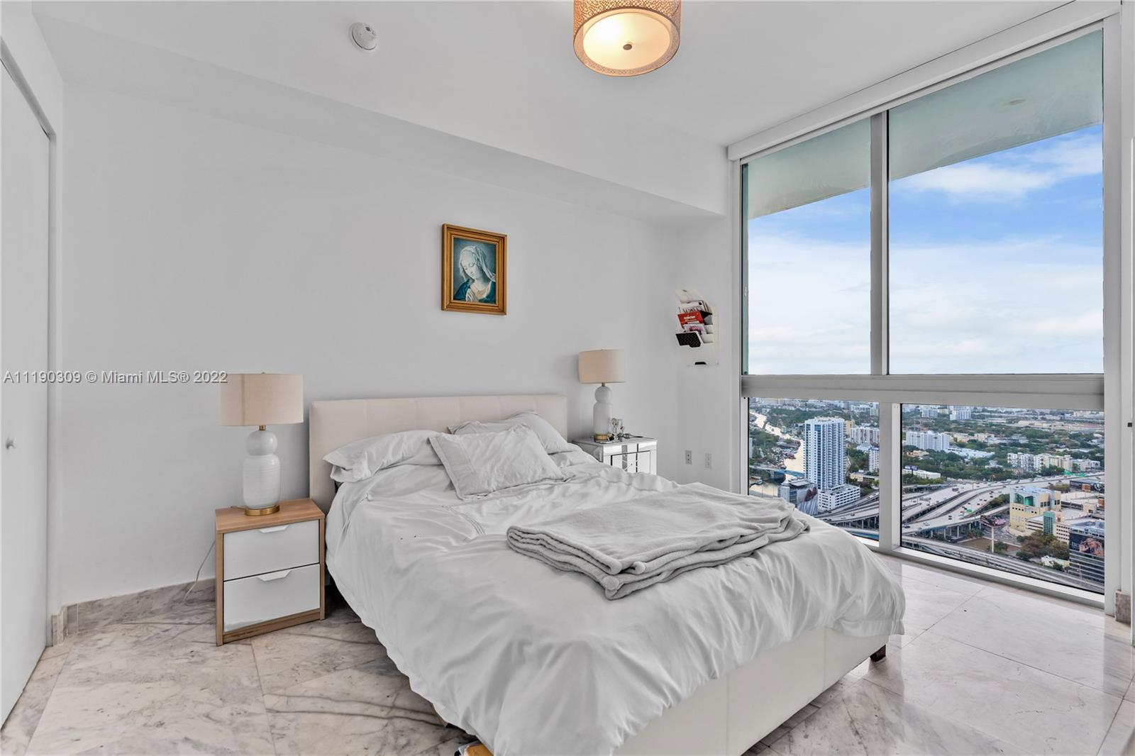 92 Southwest 3rd Street, Unit 5106 Miami, FL 33130 - Photo 21 of 36 a bedroom with a large bed and a chandelier