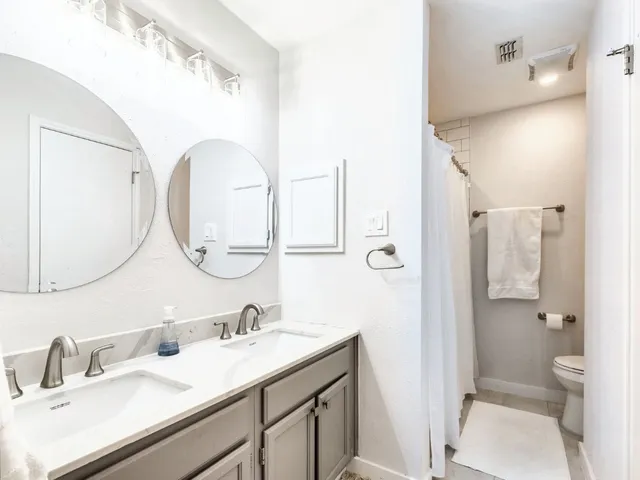 a bathroom with a granite countertop sink mirror and a toilet