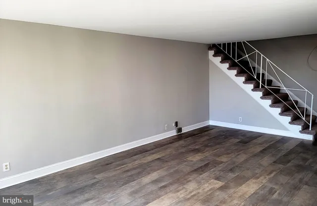 a view of an empty room with wooden floor and stairs