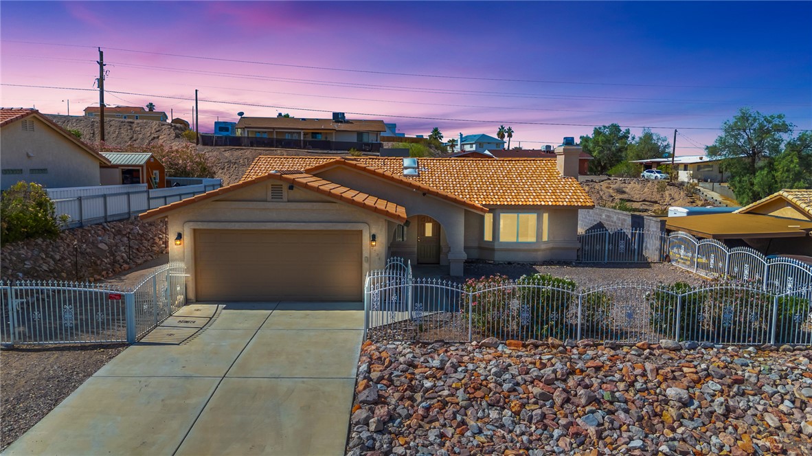 2524 South Ridge Avenue Bullhead City, AZ 86429 - Photo 2 of 64 View of front of home with a tile roof, an attached garage, stucco siding, a fenced front yard, and concrete driveway