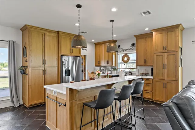 a kitchen with stainless steel appliances granite countertop a refrigerator a sink a stove a dining table and chairs