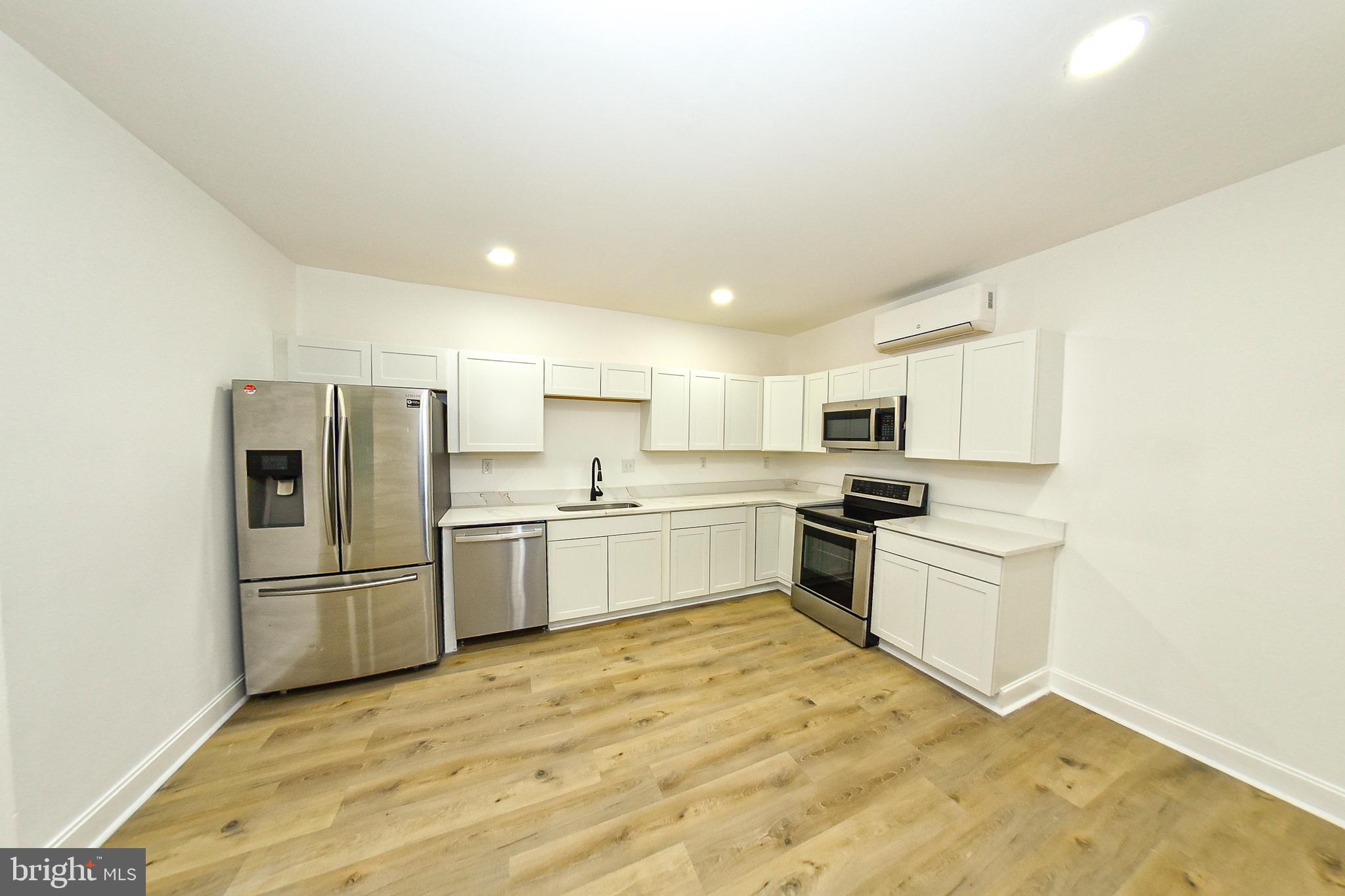 3704 Suitland Road Southeast Washington, DC 20020 - Photo 61 of 70 a kitchen with granite countertop a refrigerator oven a sink dishwasher and white cabinets with wooden floor