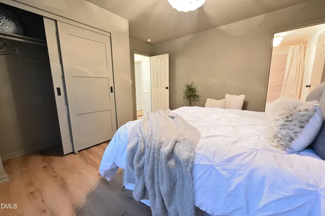 an empty room with wooden floor chandelier fan and windows