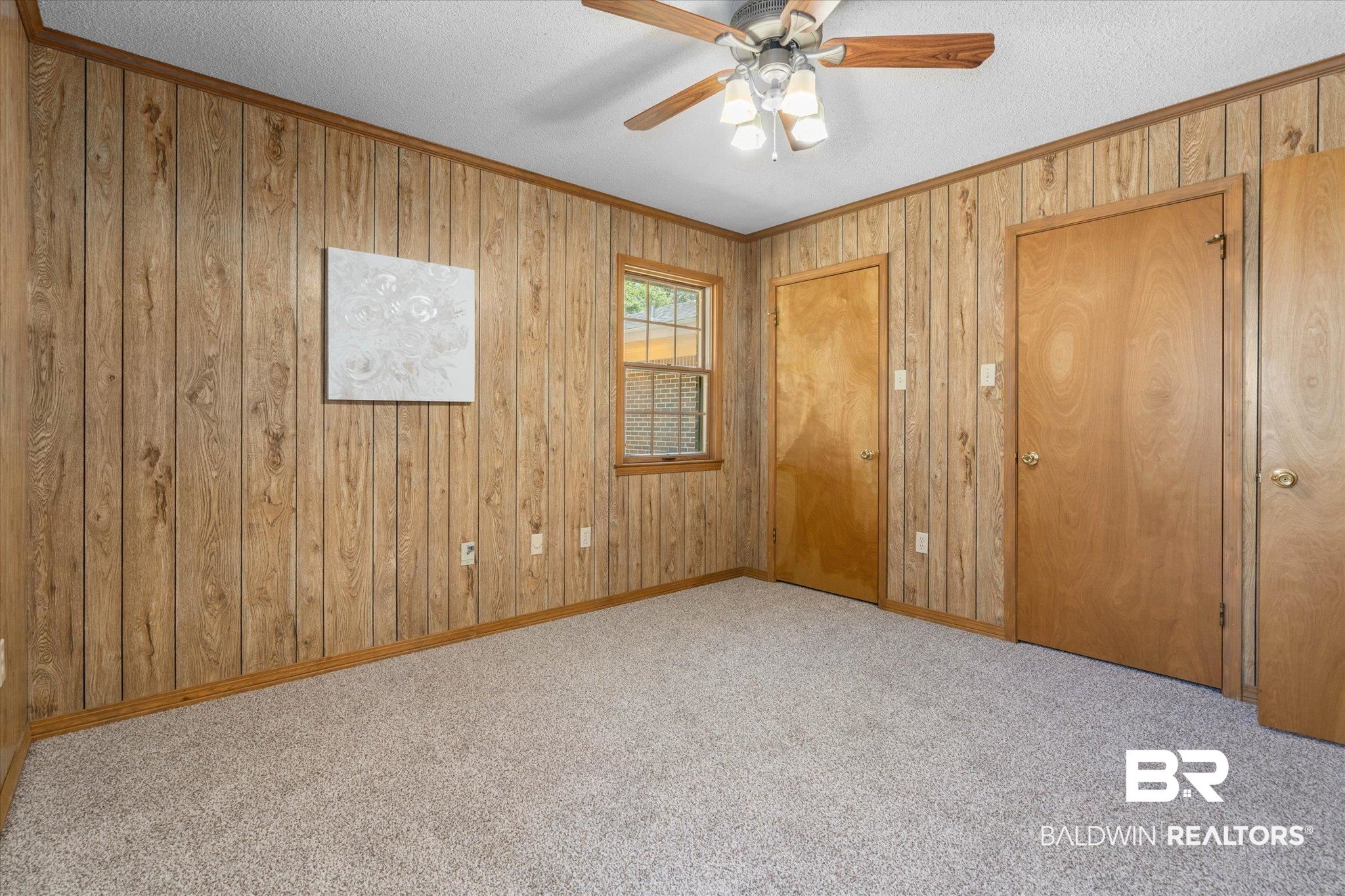 5503 Darring Street Satsuma, AL 36572 - Photo 18 of 31 Unfurnished bedroom featuring ornamental molding, carpet floors, a textured ceiling, wood walls, and a ceiling fan