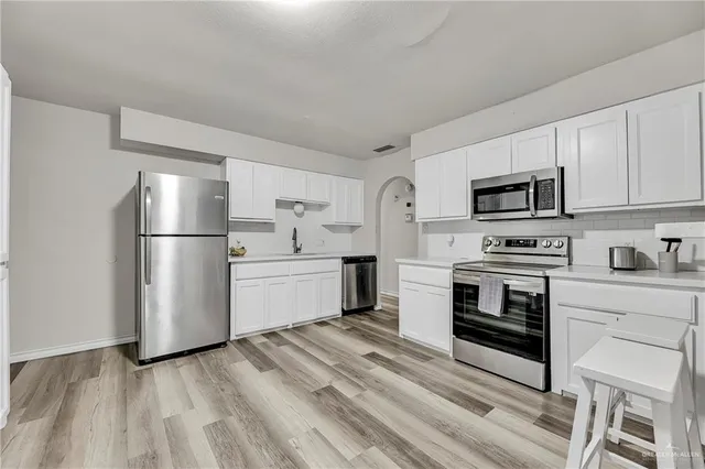 a kitchen with a refrigerator stove and white cabinets