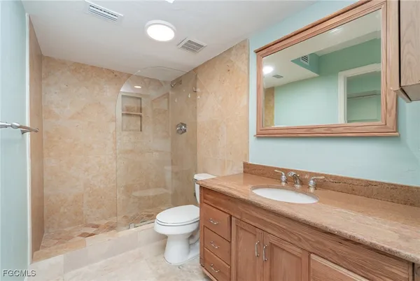 a bathroom with a granite countertop sink a toilet and a shower