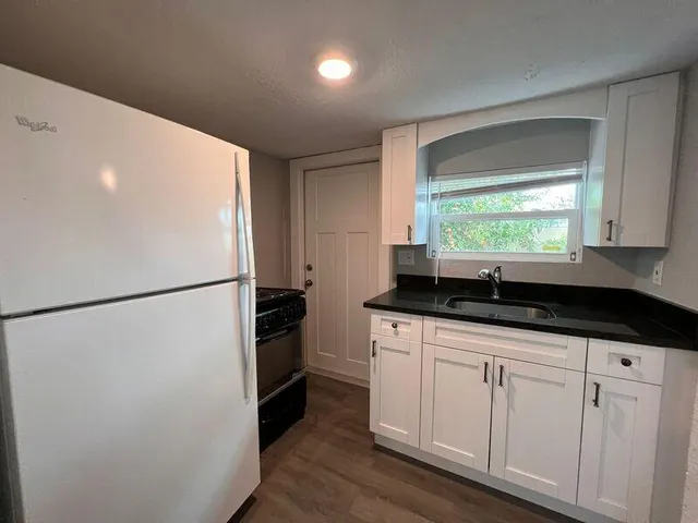 a kitchen with granite countertop white cabinets and white appliances