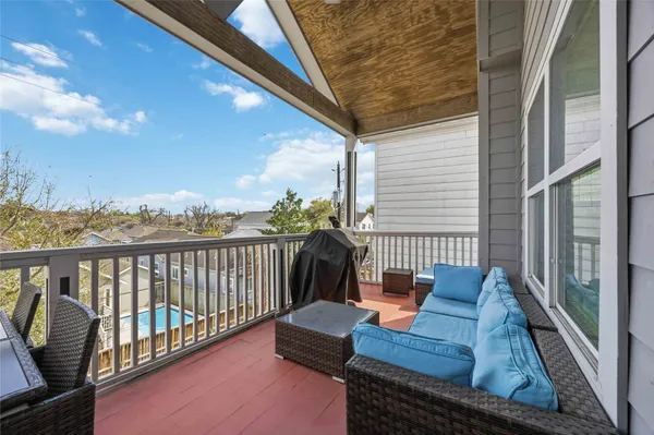 a balcony with wooden floor stairs and outdoor seating