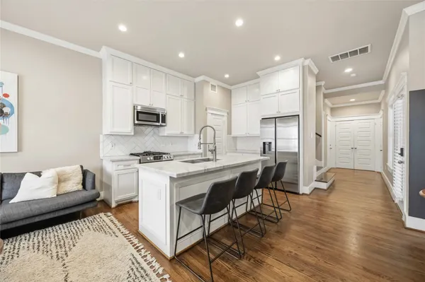 a kitchen with stainless steel appliances granite countertop a stove top oven a sink dishwasher and a refrigerator with wooden floor