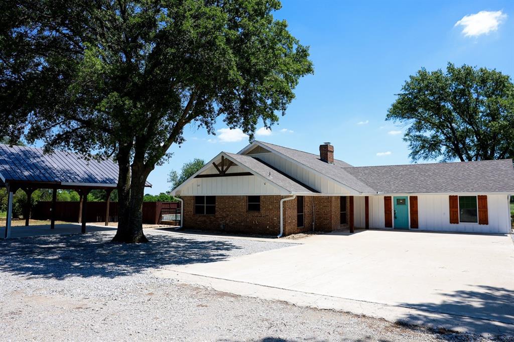 10575 Friendship Road Pilot Point, TX 76258 - Photo 31 of 32 Single-story residence featuring a brick and white siding exterior with a contrasting turquoise entry door and wood shutters