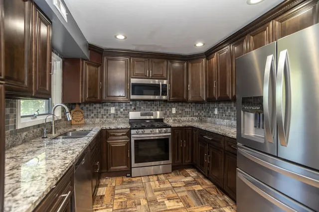 a kitchen with stainless steel appliances granite countertop a sink stove and refrigerator