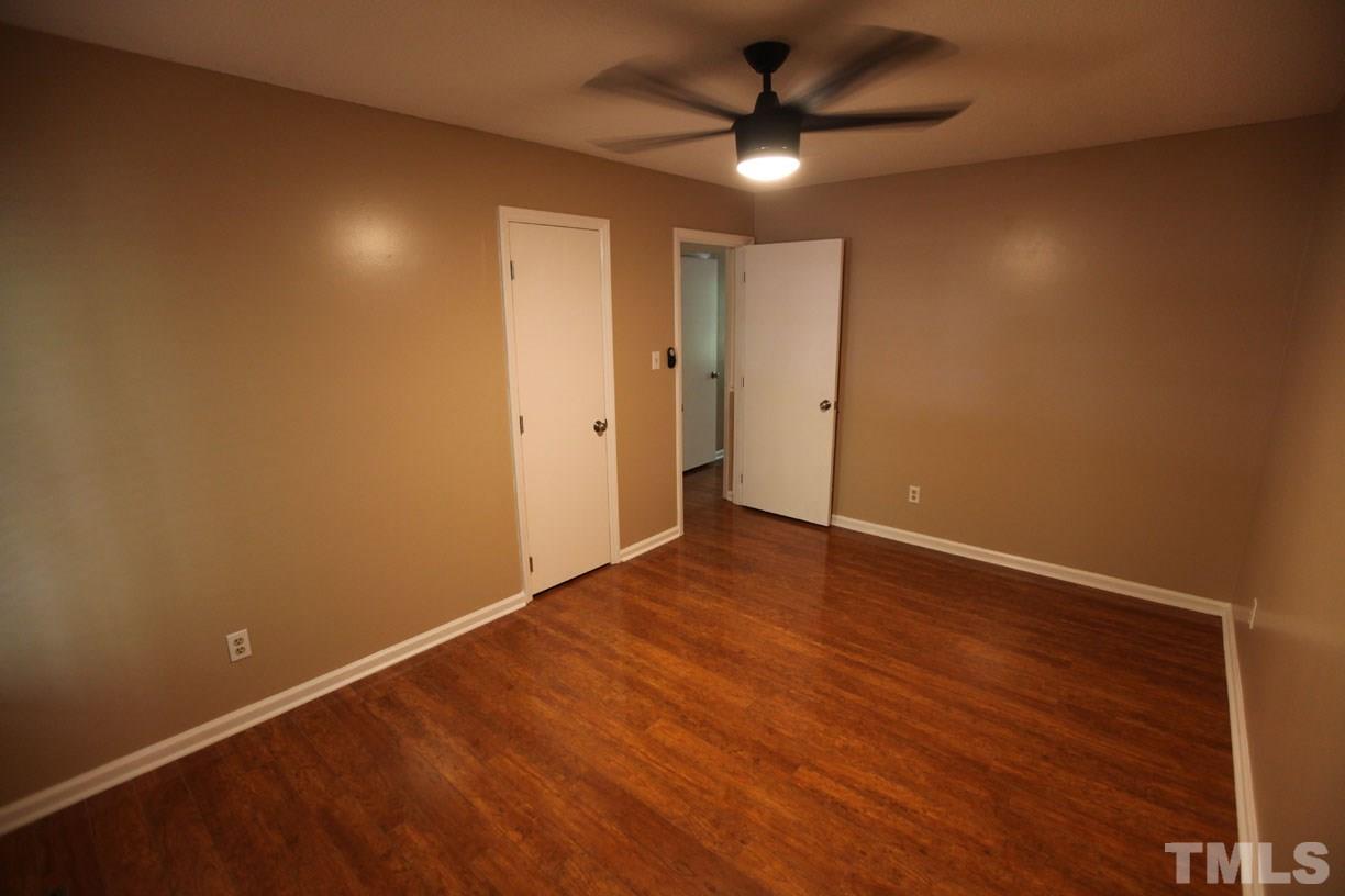 7319 Post Oak Road Raleigh, NC 27615 - Photo 9 of 12 an empty room with a ceiling fan and wooden floor