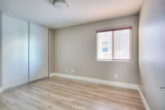 a view of an empty room with wooden floor and closet