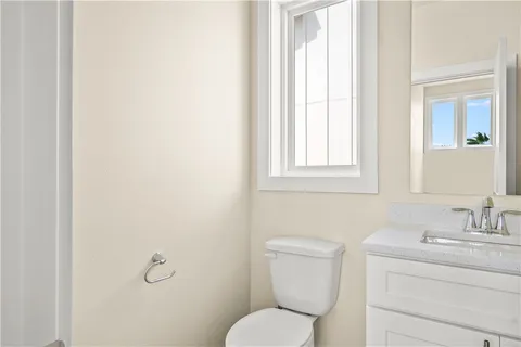 a bathroom with a toilet a sink a mirror and a window