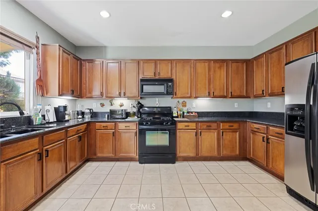 a kitchen with stainless steel appliances granite countertop a stove top oven a sink dishwasher and a refrigerator